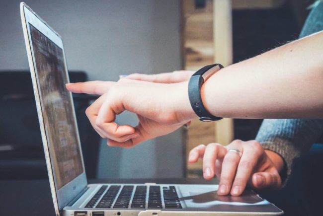 Manos de dos personas trabajando en un portátil