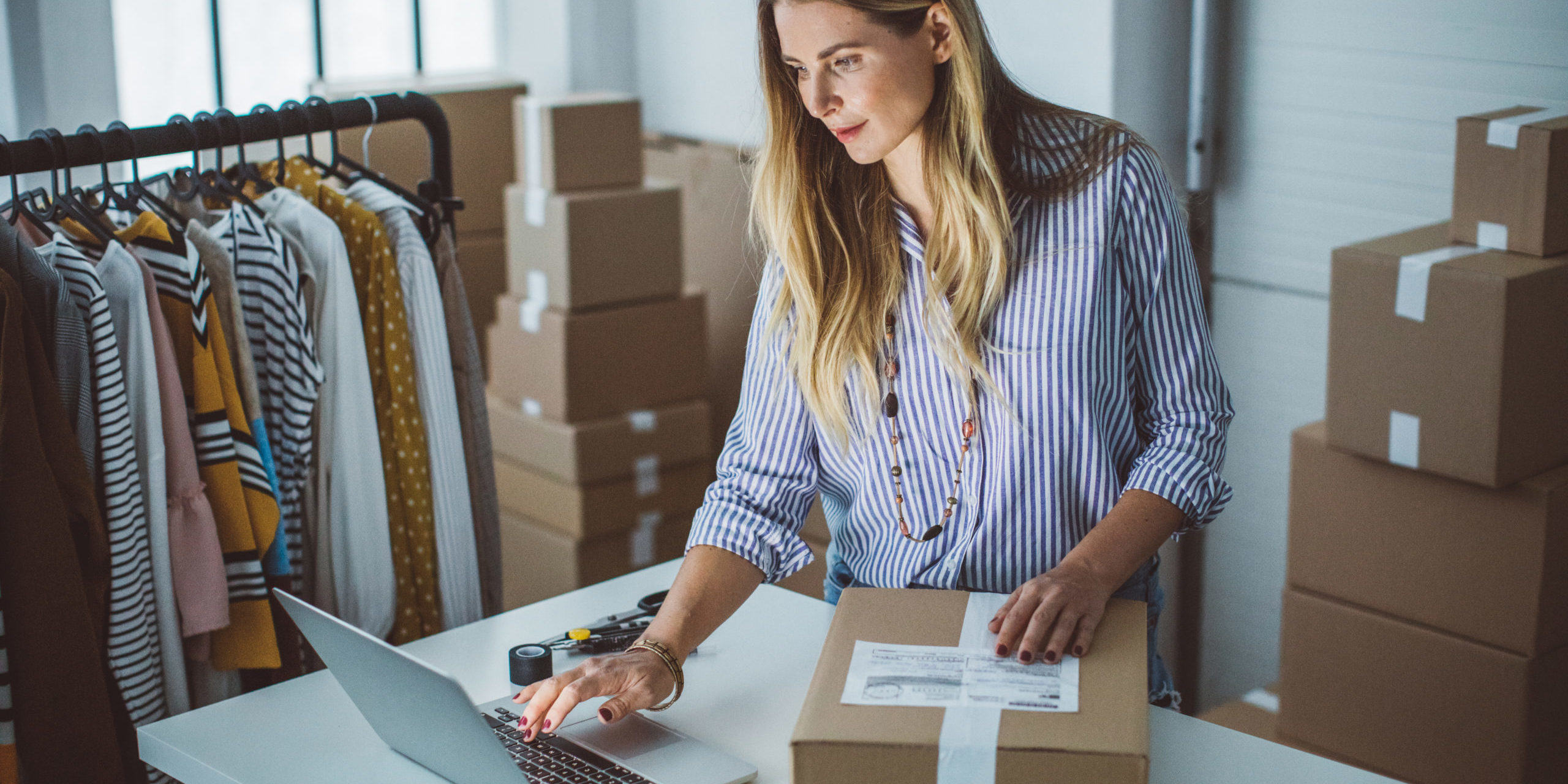 Mujer revisando pedidos y preparando paquetes de su tienda online