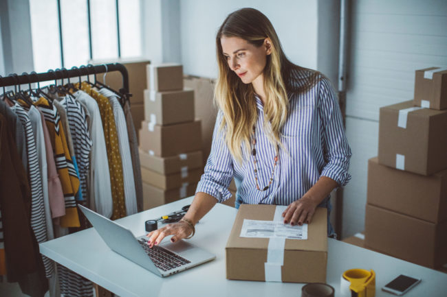 Prepara tu tienda online para las Navidades Mujer revisando pedidos y preparando paquetes de su tienda online